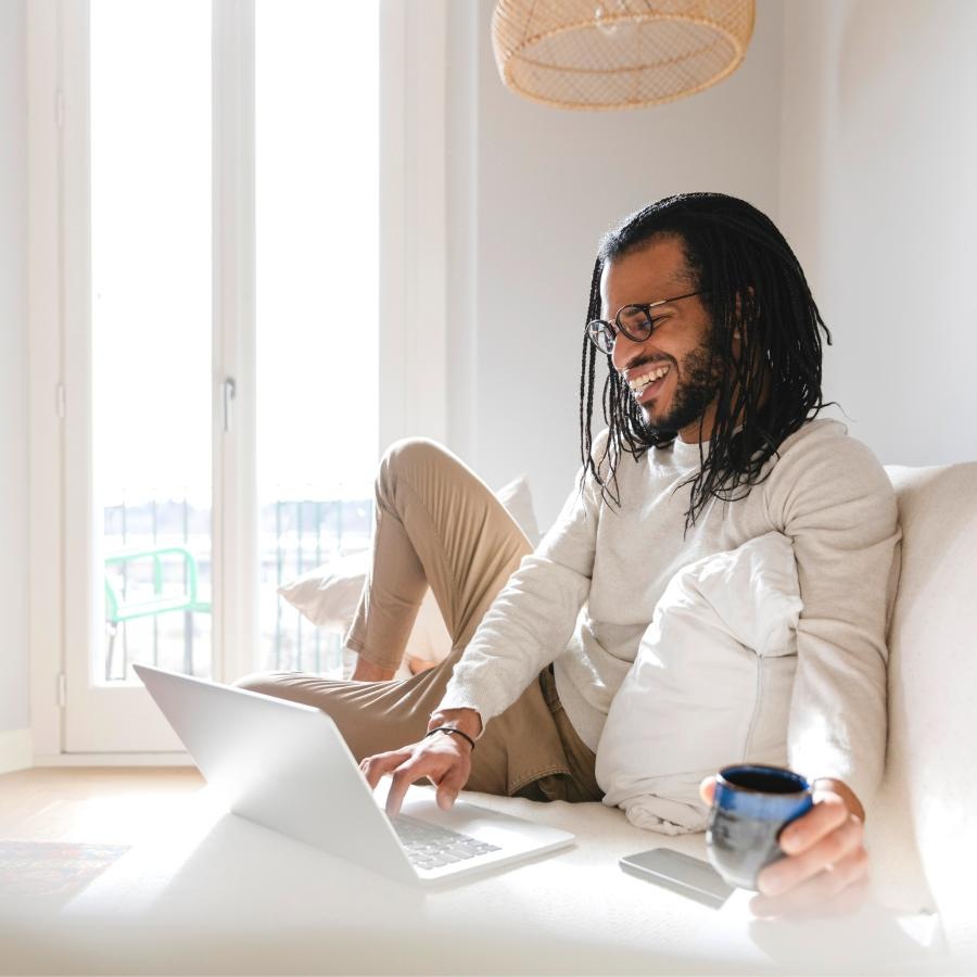 a person sitting on bed with a laptop - What are the best Arlington VA luxury apartments with river view J.Rivelle Rosslyn 